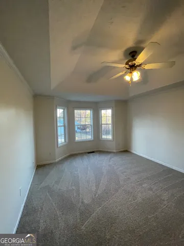 an empty room with windows and fan