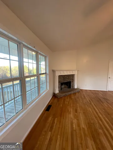 a view of empty room with wooden floor and fireplace