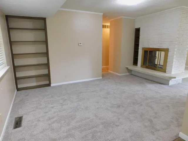a view of an empty room with a fireplace and a window