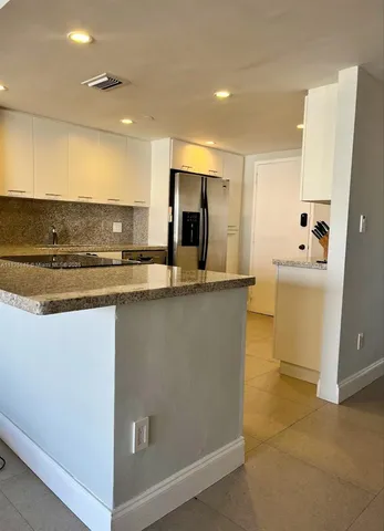 a kitchen with kitchen island sink and refrigerator