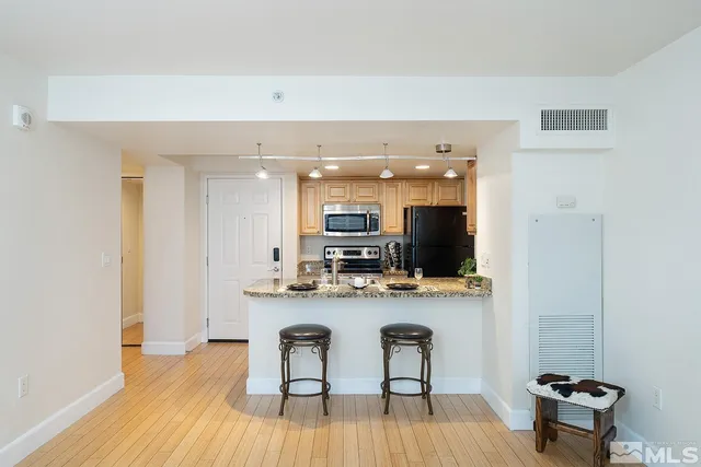 a view of a kitchen with kitchen island granite countertop wooden floor and a refrigerator