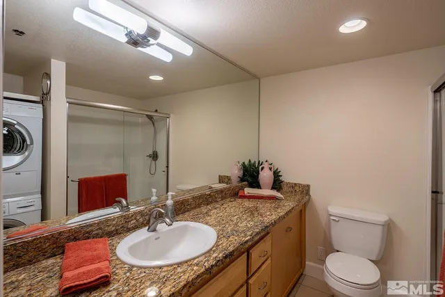 a bathroom with a granite countertop sink a mirror and a toilet