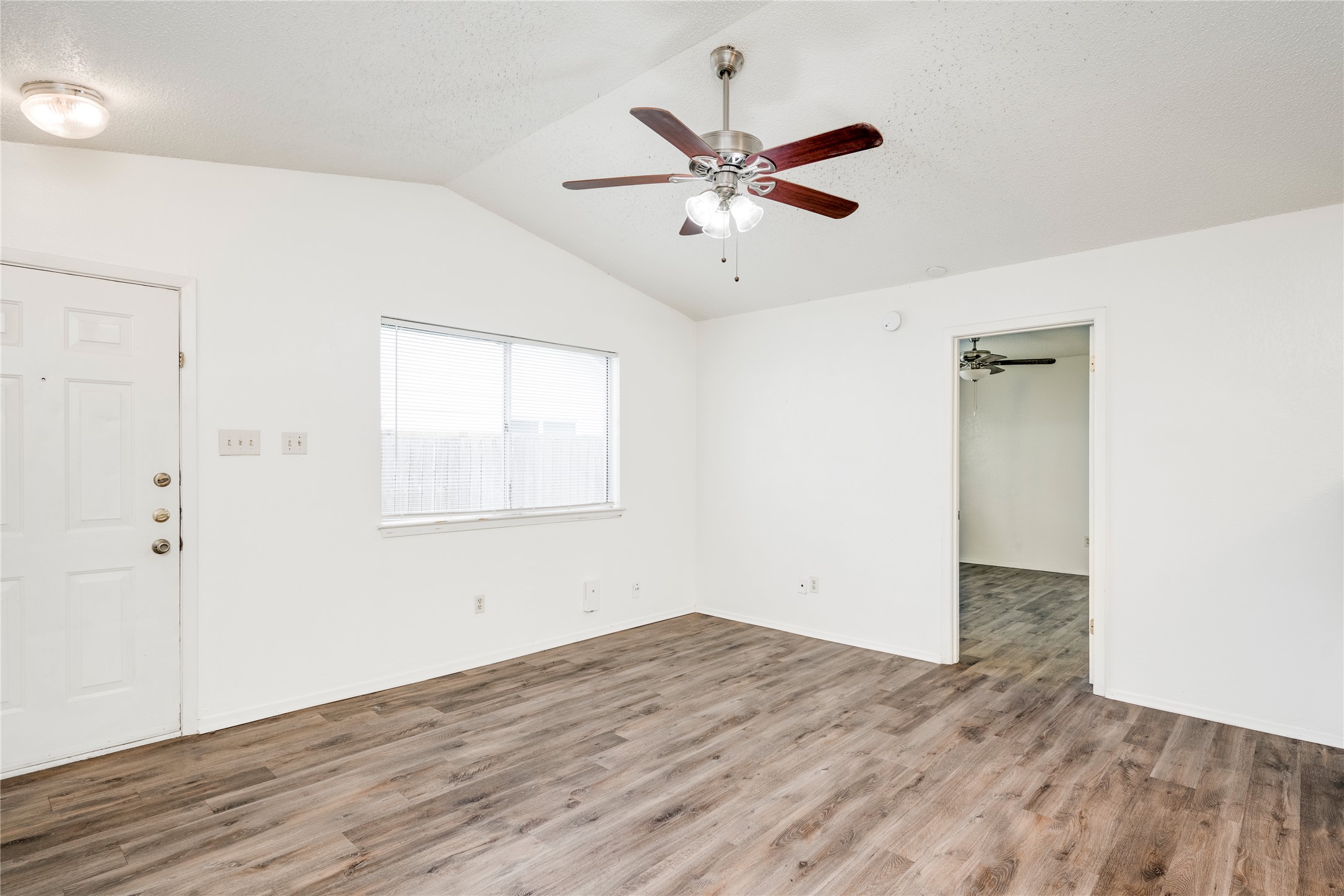 7918 West Gate Boulevard Austin, TX 78745 - Photo 15 of 31 A well-lit living area features warm wood flooring and vaulted ceilings, ready for personal touches.
