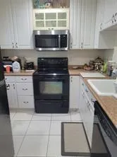 a kitchen with granite countertop a stove top oven microwave and cabinets