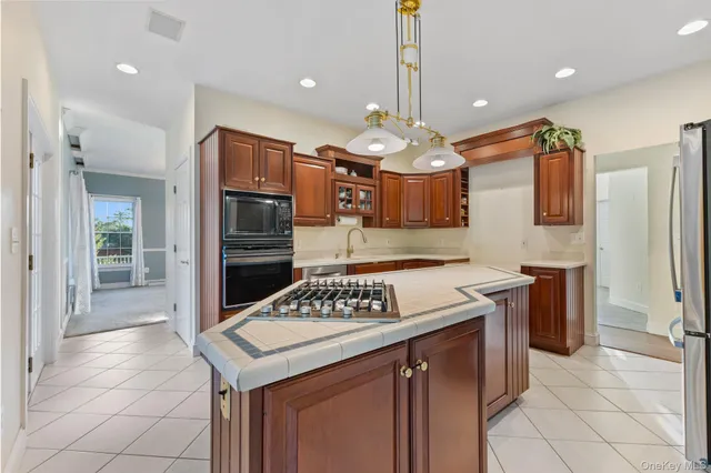 a kitchen with stainless steel appliances kitchen island granite countertop a stove a refrigerator and a oven with wooden cabinets