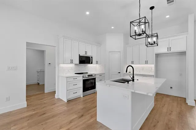 a kitchen with stainless steel appliances a sink dishwasher a refrigerator and a stove with wooden floor