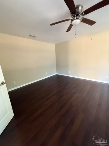 an empty room with wooden floor and fan