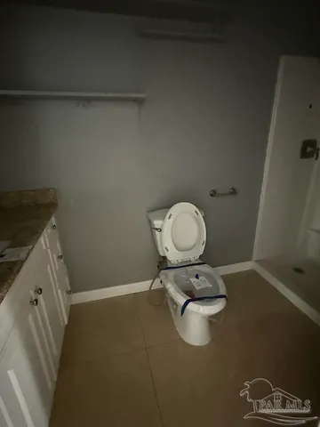 a bathroom with a granite countertop toilet and a sink