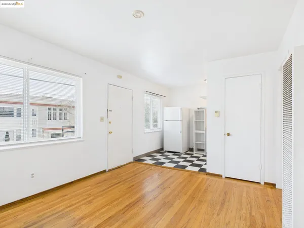 a view of an empty room with wooden floor and a window