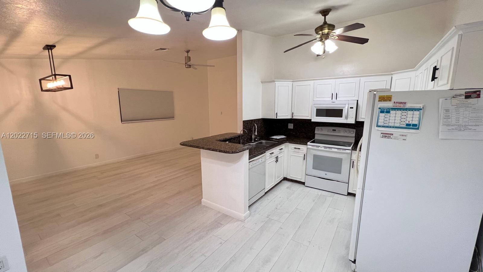 10669 Boca Entrada Boulevard Boca Raton, FL 33428 - Photo 9 of 19 a kitchen with stainless steel appliances a white stove top oven a sink dishwasher and a refrigerator with wooden floor