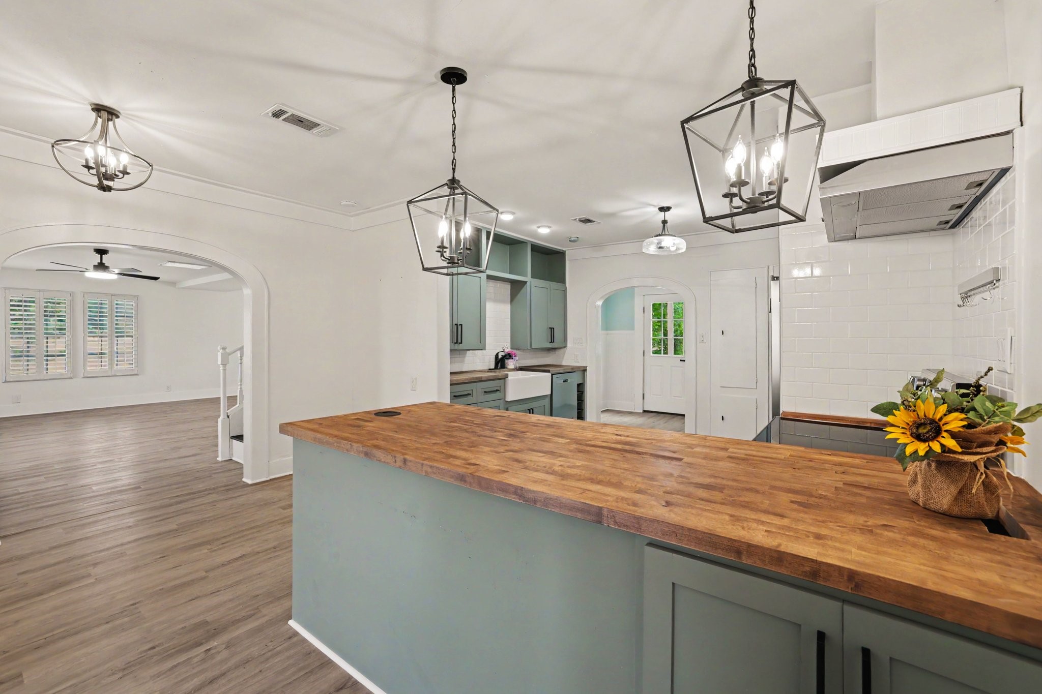 31730 Waller Tomball Road Waller, TX 77484 - Photo 15 of 50 Bright, open-concept kitchen with stylish pendant lighting, butcher block countertop, and green cabinetry.