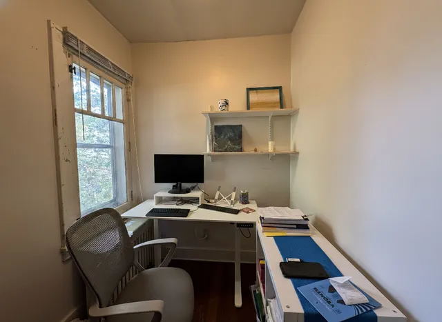 a view of a workspace with furniture and a window