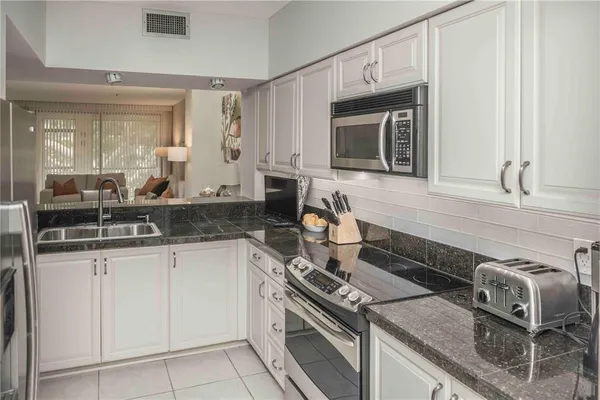 a kitchen with granite countertop a sink stove and cabinets