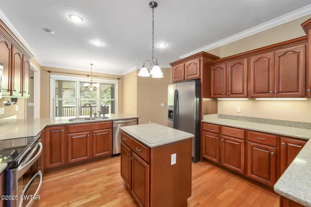 a kitchen with stainless steel appliances granite countertop a sink a stove and a refrigerator