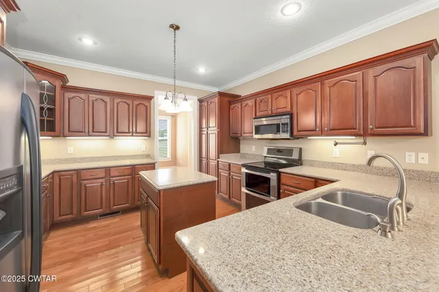 a kitchen with stainless steel appliances granite countertop wooden cabinets a stove top oven a sink and dishwasher