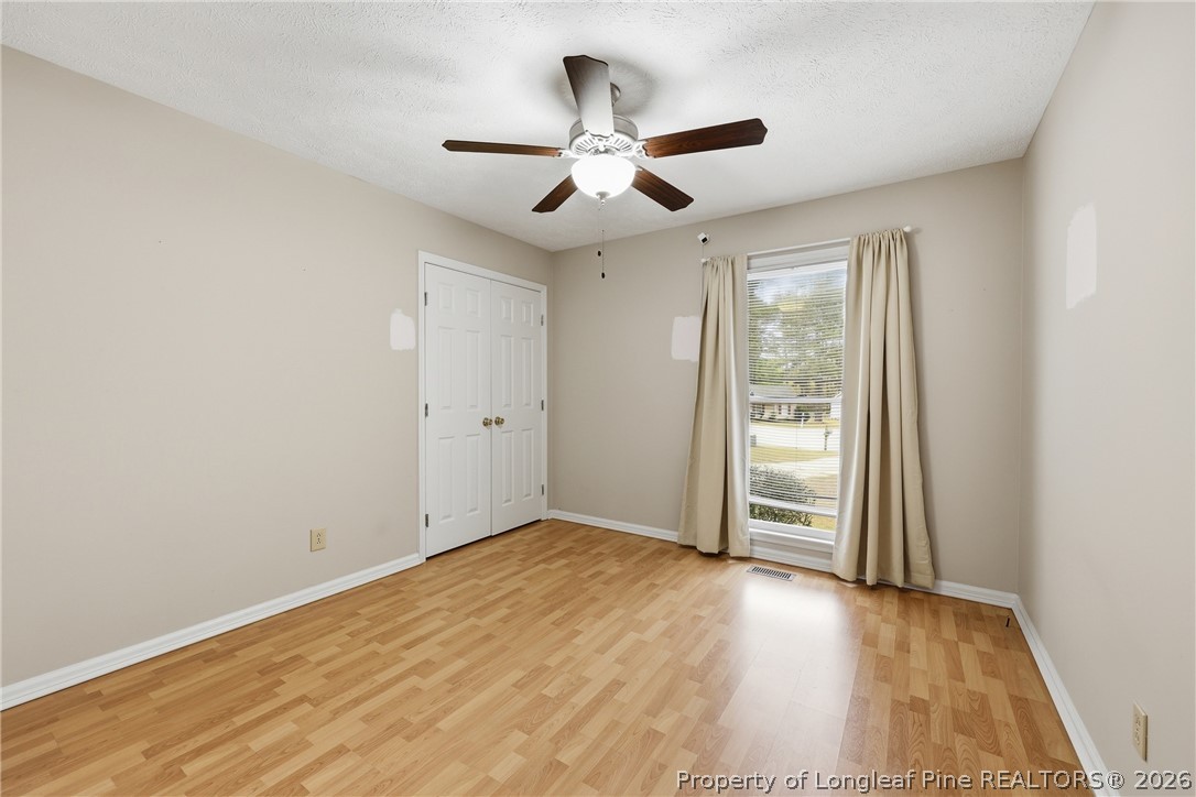 207 Cobblestone Court Raeford, NC 28376 - Photo 23 of 35 an empty room with wooden floor ceiling fan and windows