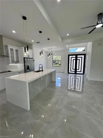 a large kitchen with stainless steel appliances kitchen island granite countertop a refrigerator and a sink
