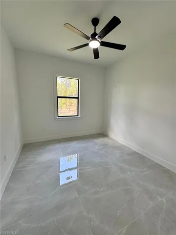 an empty room with windows and ceiling fan