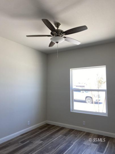 420 Thomas Street Ridgecrest, CA 93555 - Photo 9 of 13 an empty room with wooden floor fan and windows
