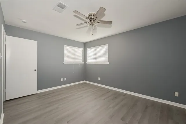 an empty room with a ceiling fan and window