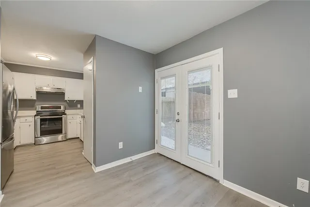 a view of kitchen with wooden floor electronic appliances and cabinets