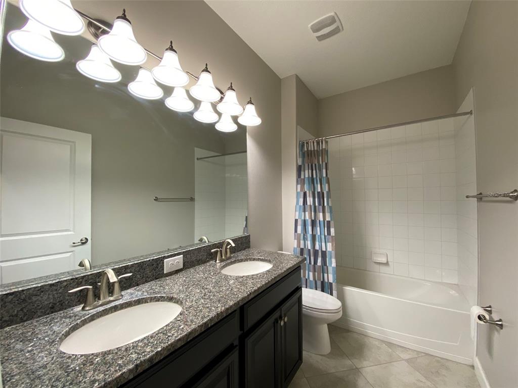 10049 Victory Gallop Loop Ruskin, FL 33573 - Photo 11 of 22 a bathroom with a granite countertop sink a toilet and shower