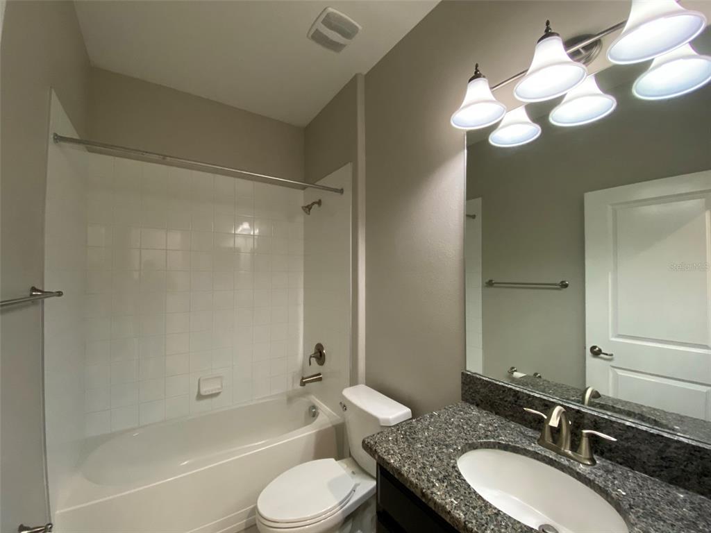 10049 Victory Gallop Loop Ruskin, FL 33573 - Photo 13 of 22 a bathroom with a granite countertop sink toilet mirror and a bathtub