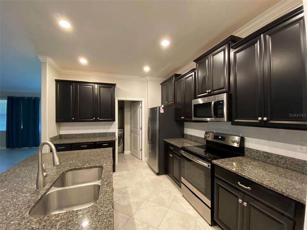 10049 Victory Gallop Loop Ruskin, FL 33573 - Photo 2 of 22 a kitchen with stainless steel appliances granite countertop a sink and a stove top oven with wooden floor
