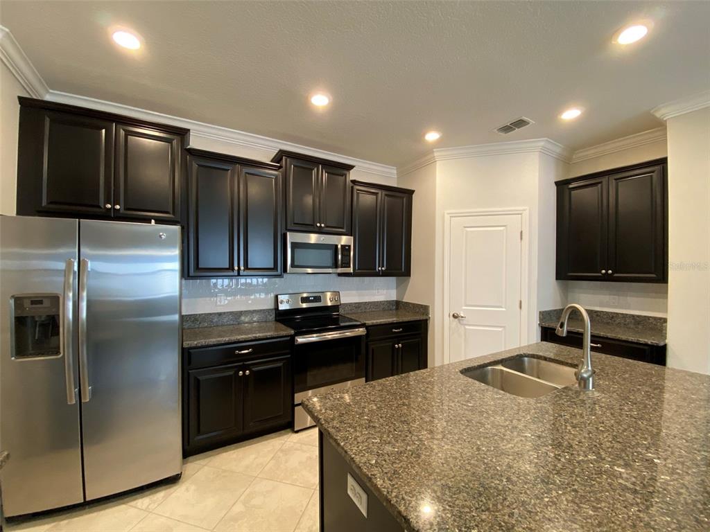 10049 Victory Gallop Loop Ruskin, FL 33573 - Photo 4 of 22 a kitchen with kitchen island granite countertop stainless steel appliances and a counter top