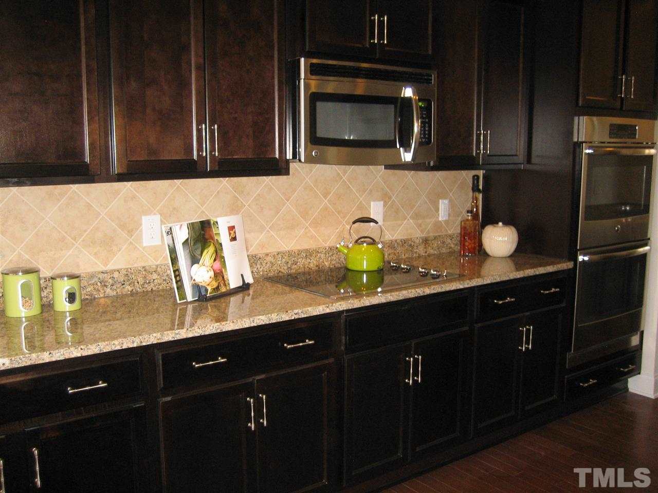2445 Everstone Road Wake Forest, NC 27587 - Photo 7 of 22 Rich Kona stained Cabinets, Granite countertops and tile Backsplash