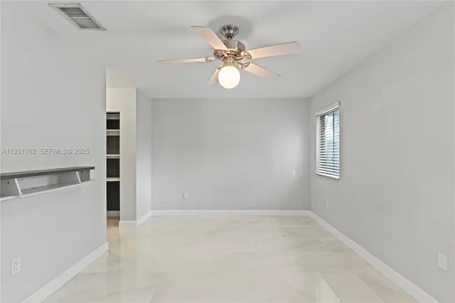 an empty room with a ceiling fan and window