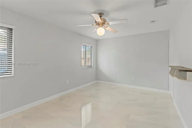 a view of an empty room with a chandelier fan