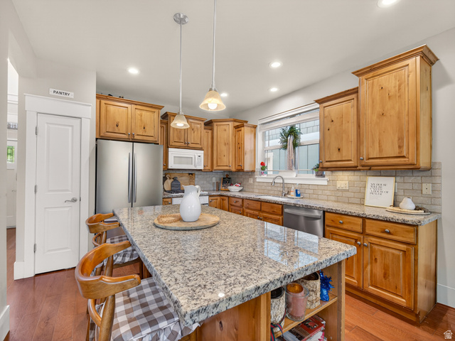 557 Craftsman Way Midway, UT 84049 - Photo 17 of 59 Kitchen featuring a large central island with a light-colored countertop, wood-finish flooring, recessed lighting, and wooden cabinetry