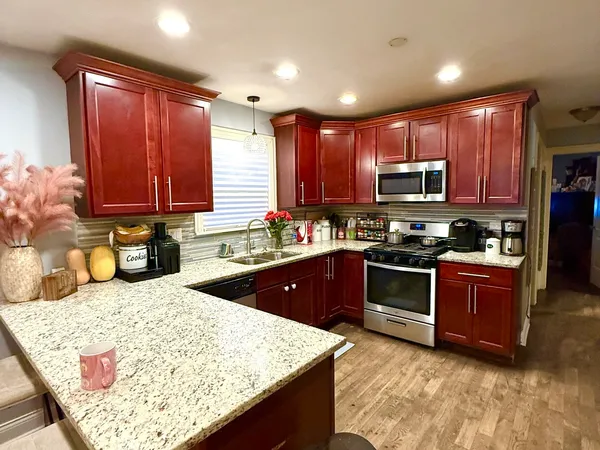 a kitchen with stainless steel appliances granite countertop wooden cabinets a stove a sink and a microwave