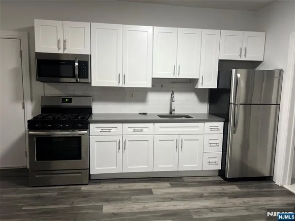 a kitchen with granite countertop white cabinets and stainless steel appliances