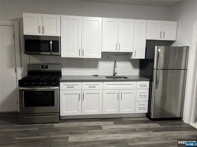 a kitchen with granite countertop white cabinets and stainless steel appliances