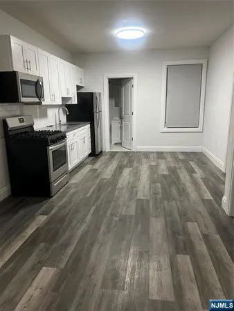 a kitchen with granite countertop a refrigerator oven a sink dishwasher and wooden cabinets