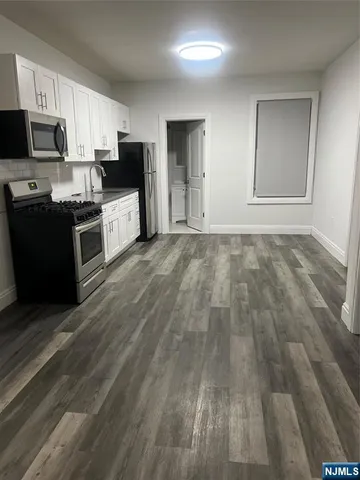 a kitchen with granite countertop a refrigerator oven a sink dishwasher and wooden cabinets