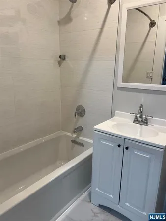 a bathroom with a bathtub sink vanity and mirror