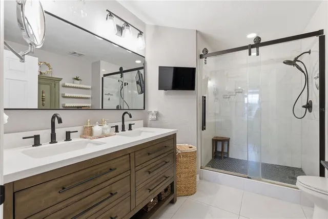 a bathroom with a double vanity sink a large mirror and shower