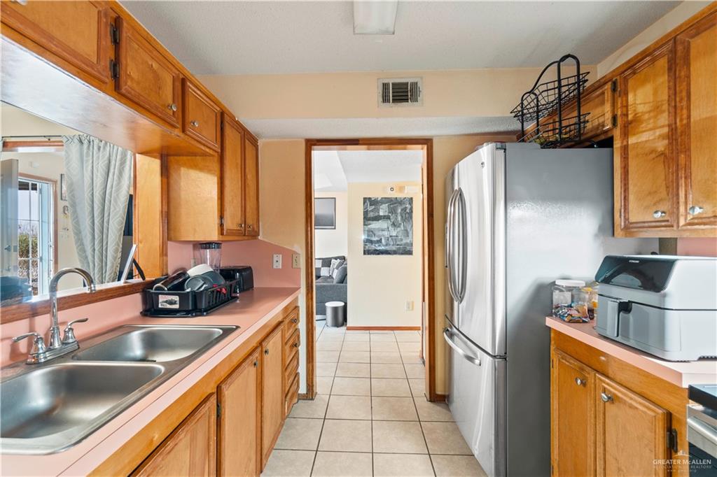 106 Rosa Priego Street Donna, TX 78537 - Photo 7 of 25 Kitchen with stainless steel refrigerator, sink, and light tile patterned floors