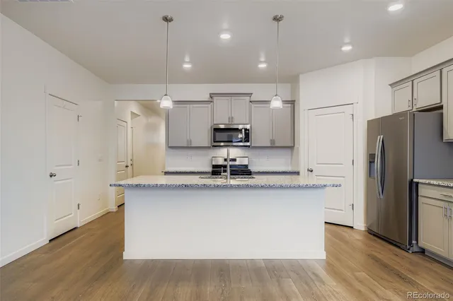 a kitchen with stainless steel appliances granite countertop a sink a refrigerator and a stove