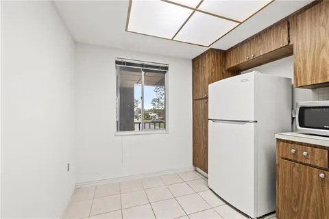 a view of a refrigerator in kitchen and an empty room