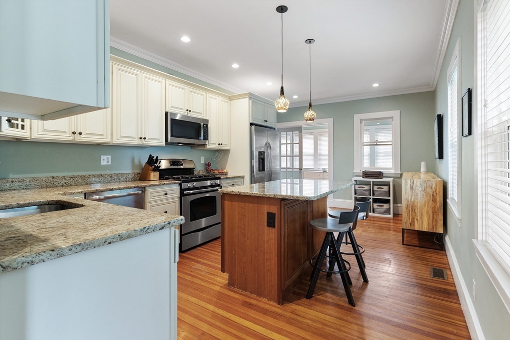 16 Orvis Road, Unit 1 Arlington, MA 02474 - Photo 11 of 31 a kitchen with stainless steel appliances granite countertop a refrigerator a stove top oven a sink dishwasher a dining table and chairs with wooden floor