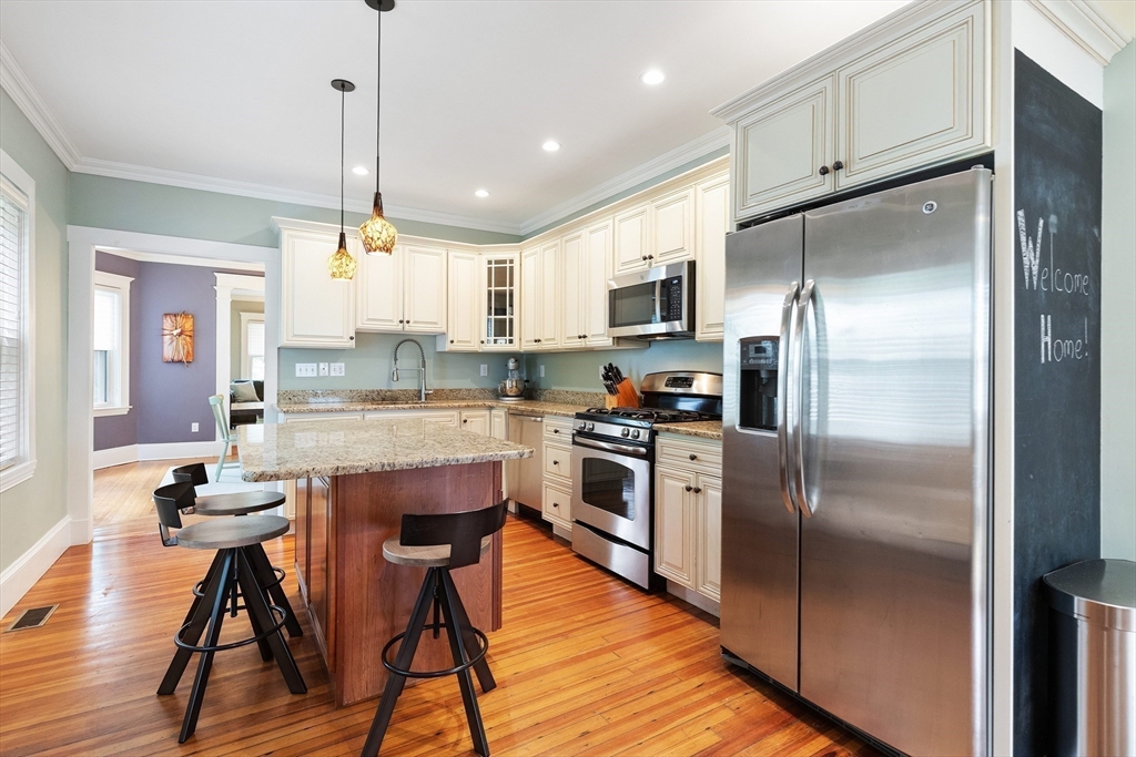 16 Orvis Road, Unit 1 Arlington, MA 02474 - Photo 13 of 31 a kitchen with stainless steel appliances granite countertop a refrigerator a stove a sink a dining table and chairs with wooden floor