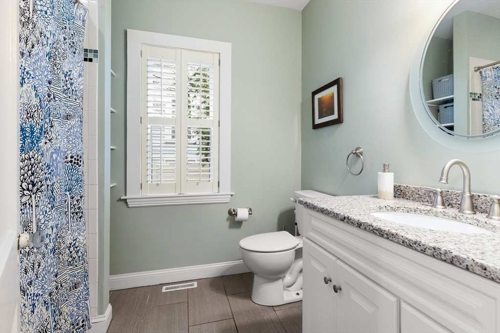 16 Orvis Road, Unit 1 Arlington, MA 02474 - Photo 18 of 31 a spacious bathroom with a granite countertop toilet a sink and a mirror