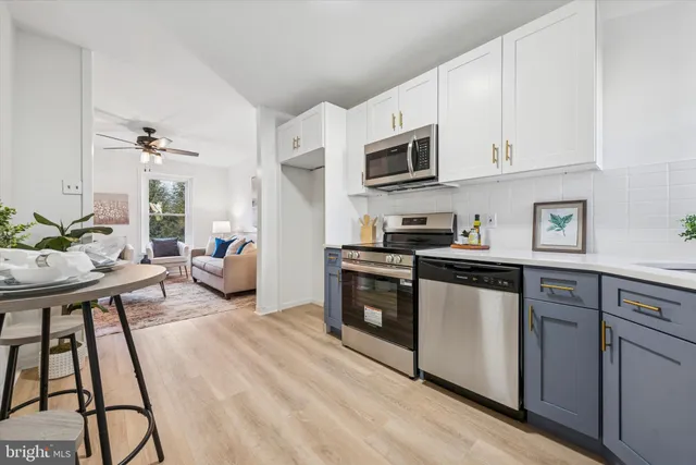 a kitchen with stainless steel appliances granite countertop a stove a sink dishwasher and white cabinets with wooden floor