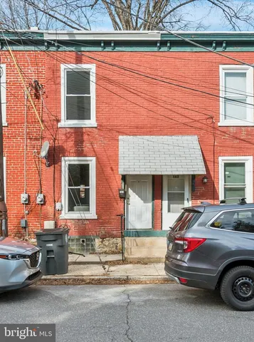 a front view of a house with cars parked on the roadside