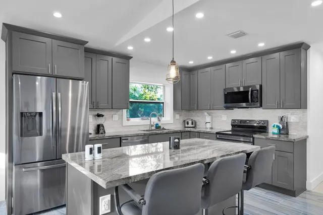 a kitchen with stainless steel appliances granite countertop a refrigerator a sink a stove a microwave and wooden cabinets