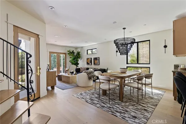 a dining room with wooden floor a chandelier a glass table and chairs